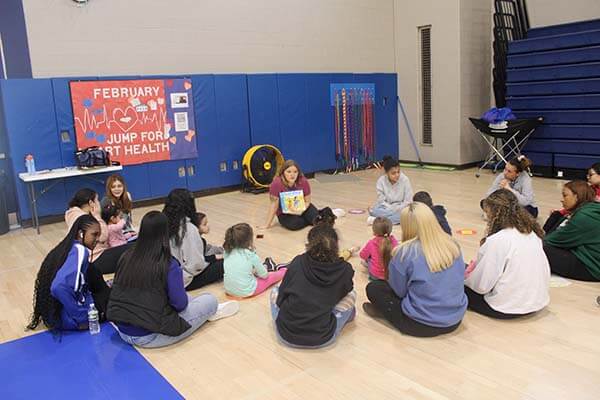 students and children sitting together in gym